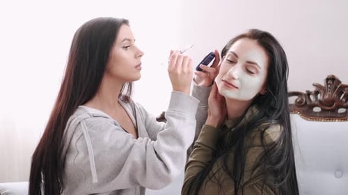 Woman Applying Facial Mask to a Friend