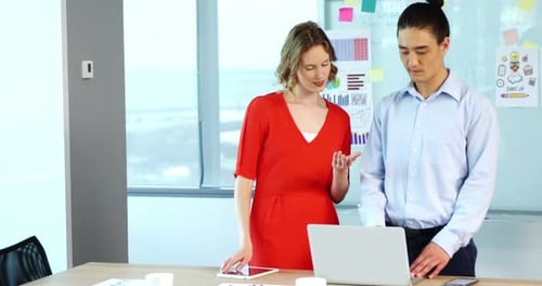 Business Colleagues Discussing Data on Laptop and Tablet