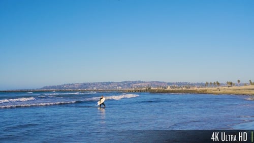 4K Surfer Guy with Surfboard Walking out of Water Towards Beach