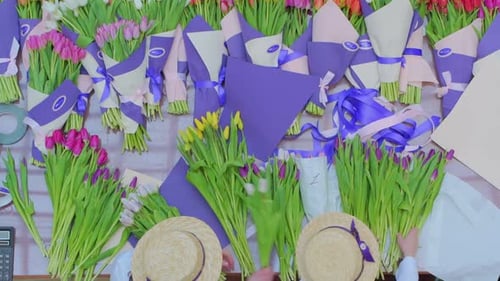 Girl Florist Is Packing Beautiful Tulips in a Flower Shop in Kraft Paper