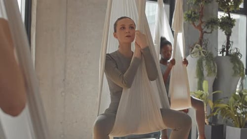 Women Doing Aerial Yoga Exercises in Hammocks