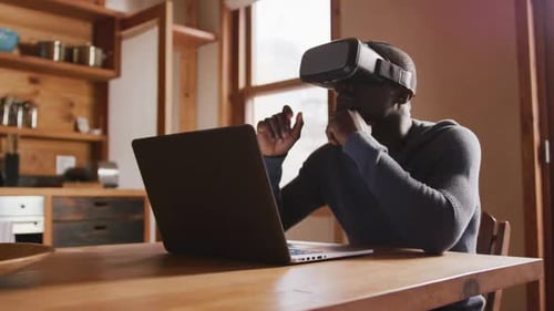 Man Using VR Headset with Laptop in Home