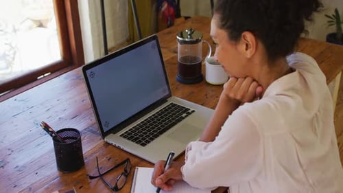 Woman Works at Laptop and Writes Notes at Home