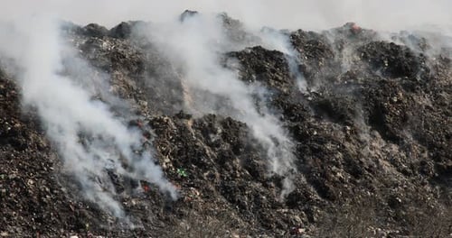 Close up of landfill with burning trash piles
