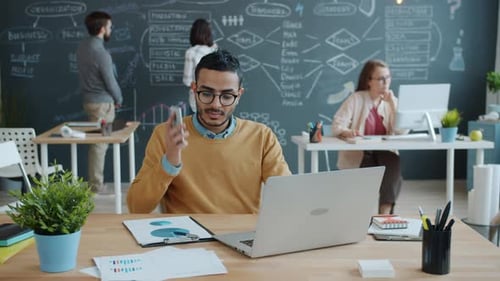 Afro-American Businessman Working with Laptop Then Talking on Mobile Phone in Shared Office