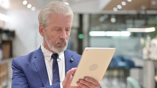 Senior Man Using Tablet in Modern Office