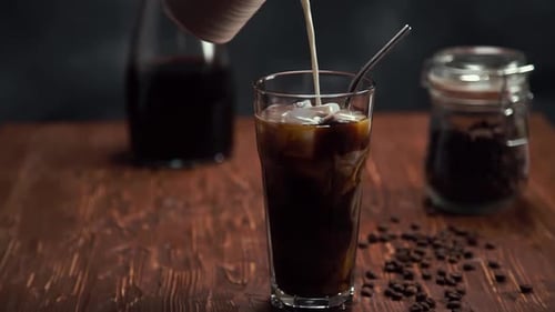 Milk Poured Into Iced Coffee Beverage in Glass