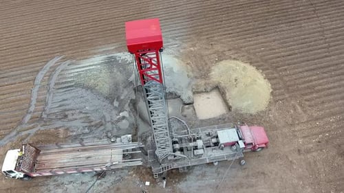 Bohranlage arbeitet auf flachem landwirtschaftlichem braunem Feld