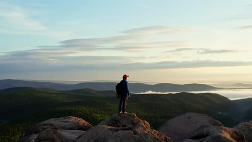 Aerial Shot of a Lone Man on Top of a Mountain at Dawn