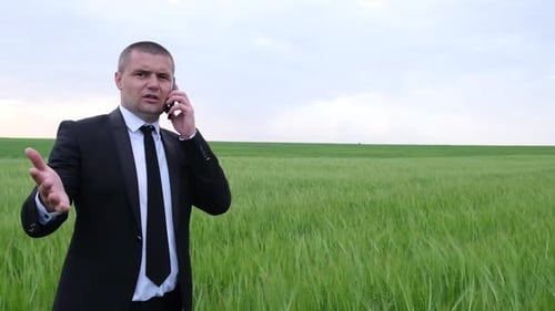 Handsome Young Businessman Talking on Smartphones in the Field