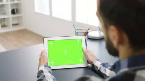 Homme touchant l'écran vert d'un ordinateur de table numérique