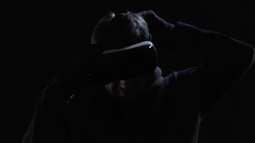 Man Putting On VR Headset in Dark Room