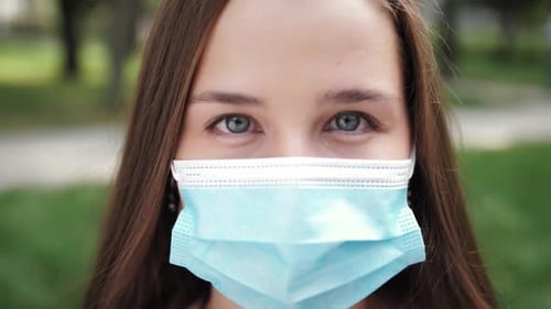 Woman Removes Face Mask and Smiles to Camera