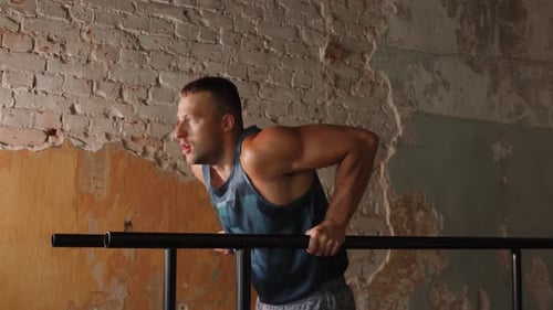 Mann, der Trizeps macht, taucht im Fitnessstudio auf Barren