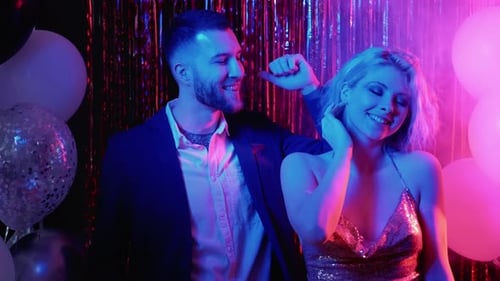 Happy Couple Dancing at Party with Balloons and Tinsel
