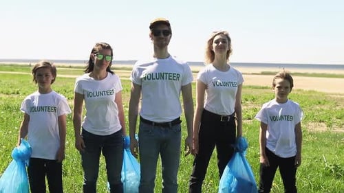 Smiling Volunteers Holding Trash Bags on Beach