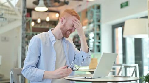 Redhead Man with Headache in Cafe Working on Laptop