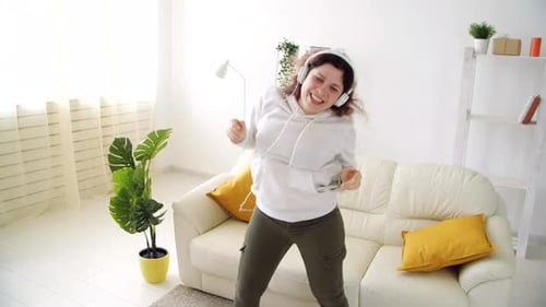 Woman Dances Energetically with Headphones in Living Room