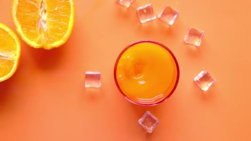 Top View of a Glass of Orange Juice with Ice on Color Background