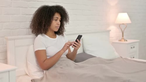 Young Adult Using Smartphone in Bed at Night