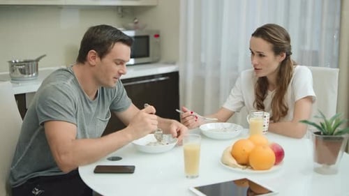 Couple Eating Breakfast and Talking in Kitchen