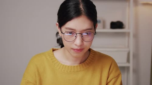 Beautiful young Asian female sitting in home office.