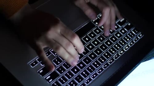 Hands Typing on Computer Keyboard at Night