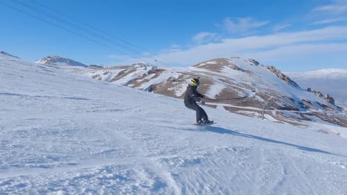 Person Snowboarding Down a Snow Covered Mountain