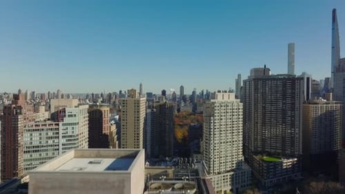 Rising Footage of Tall Buildings Revealing View of Various Buildings in City and Autumn Foliage in