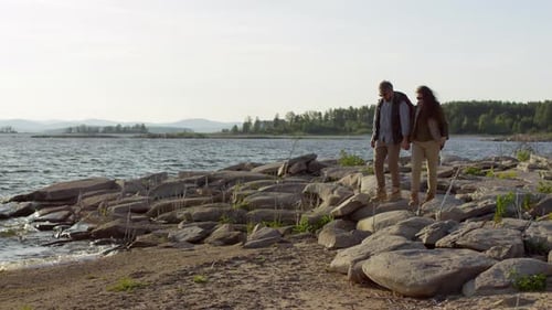 Romantisches Touristenpaar spaziert auf Rocky Lakeshore
