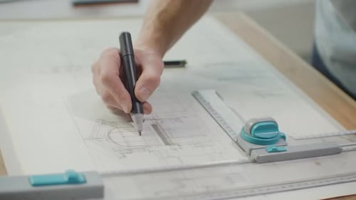 Der Ingenieur zeichnet mit einem Bleistift und einem Lineal Gebäude auf den Tisch