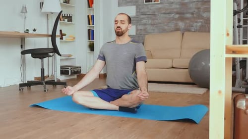 Man Meditating on Yoga Mat in Living Room
