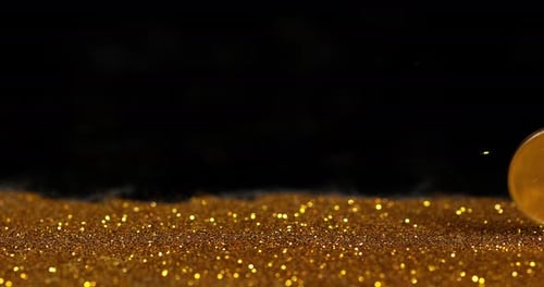 Münze von 1 Euro auf Goldpulver vor schwarzem Hintergrund, Zeitlupe 4K