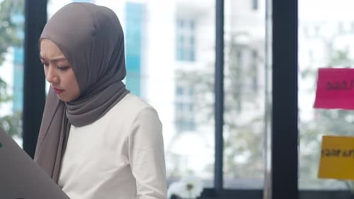 Asia muslim lady drawing work plan think information reminder on paper in new normal office.