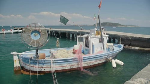 Altes Fischereifahrzeug mit Treibnetzen, in der Nähe von Pier geparkt und auf Wellen schwimmend
