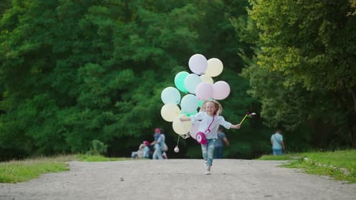 Joyful child holds many balloons in the park