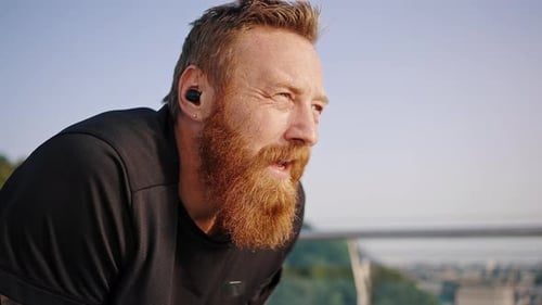 Exhausted Runner with Long Beard Breathes Deep Wiping Sweat