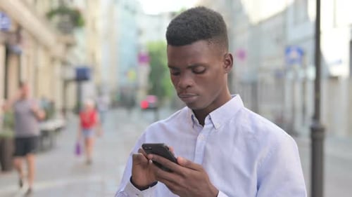 Young Adult Using Smartphone in City Street