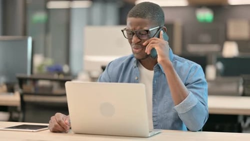 Young Adult Talking on Phone at Office Desk