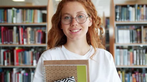 Portrait of Student Pretty Girl Holding Books in University Library Smiling