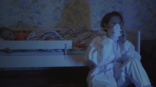 Worried Woman Removing PPE in Child's Bedroom