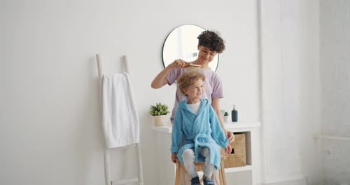 Mother Brushes Child's Hair in Bright Bathroom