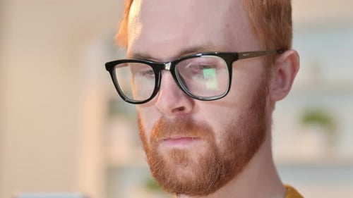 Nahaufnahme des Gesichts des rothaarigen Mannes mit digitalem Gerät