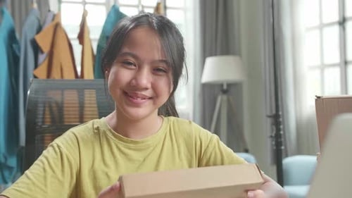 Young Woman Holding Box Smiling in Office