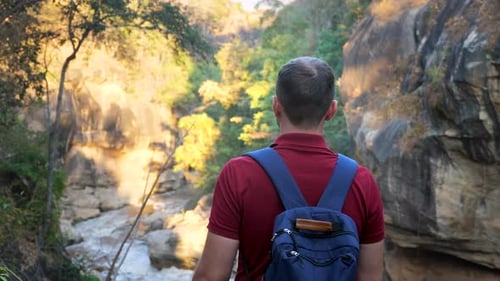 Male Tourist with Backpack Travels in Natural Park on Foot During Sunset
