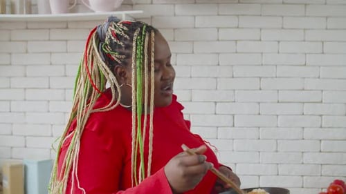Woman Cooking Food and Tasting in Modern Kitchen