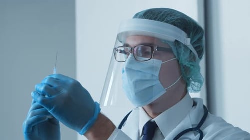 Studio portrait of young professional medical doctor in mask, hat and protective visor.