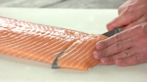 Hands Slice Fresh Salmon Fillet with Sharp Knife