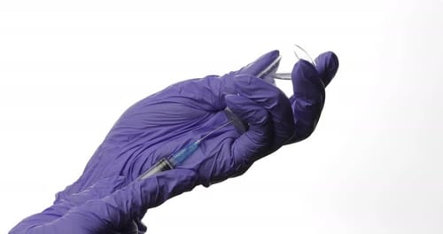Gloved Hand Draws Liquid from Vial with Syringe