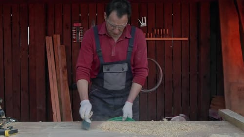 Man Sweeping Sawdust in Woodworking Workshop